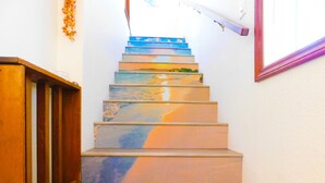 A staircase with a wooden handrail and a series of steps painted with a beach scene.