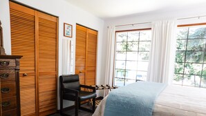 A bedroom with a bed, wooden wardrobe, a chair, and a window with curtains. - Footsteps to Pebble Beach & Short Drive to Redwoods (Crescent City)