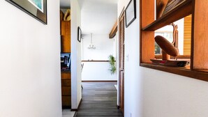 A narrow hallway with wooden floors, white walls, and a wooden door.