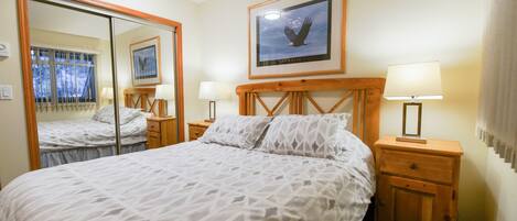 A hotel room with a large bed, two bedside tables with lamps, a mirror, and a framed picture on the wall.