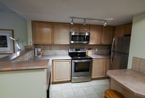 A kitchen with wooden cabinets, stainless steel appliances, and a tiled backsplash. - Stoney Creek Lagoons 32 (Whistler)