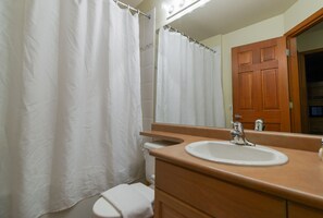 Een badkamer met een witte douchegordijn, een wastafel en een toilet.