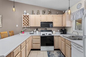 A modern kitchen with wooden cabinets, a microwave, stove, and a sink. - Lazy Days X-09 - Three Bedroom Apartment, Sleeps 8 (Osage Beach)