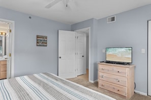 A bedroom with a bed, a dresser, a television, and a door. - Lazy Days X-09 - Three Bedroom Apartment, Sleeps 8 (Osage Beach)