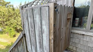 A wooden deck with a wooden privacy screen and a window with a view of the outdoors. - Sunspace:  Quiet location, screened porch, deck, treetop sunsets (Ocracoke)