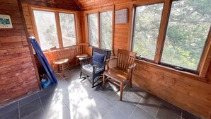 A cozy cabin interior with wooden walls, large windows, and a tiled floor. - Sunspace:  Quiet location, screened porch, deck, treetop sunsets (Ocracoke)
