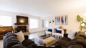 Una sala de estar con chimenea, un televisor grande y un cuadro en la pared.