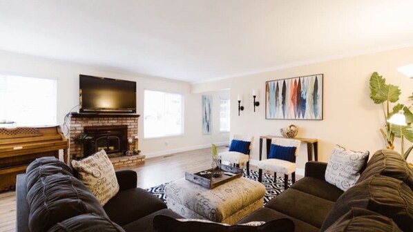 Una sala de estar con chimenea, un televisor grande y un cuadro en la pared.