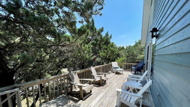 Eine Holzterrasse mit Gartenmöbeln, umgeben von Bäumen.
