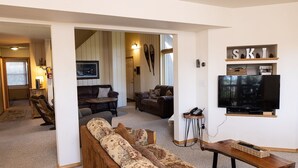 A living room with a sofa, a coffee table, a TV, and a fireplace. - Spacious Home with Ski Access (Whitefish)