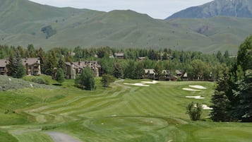 A golf course with a clubhouse and residential buildings in the background.