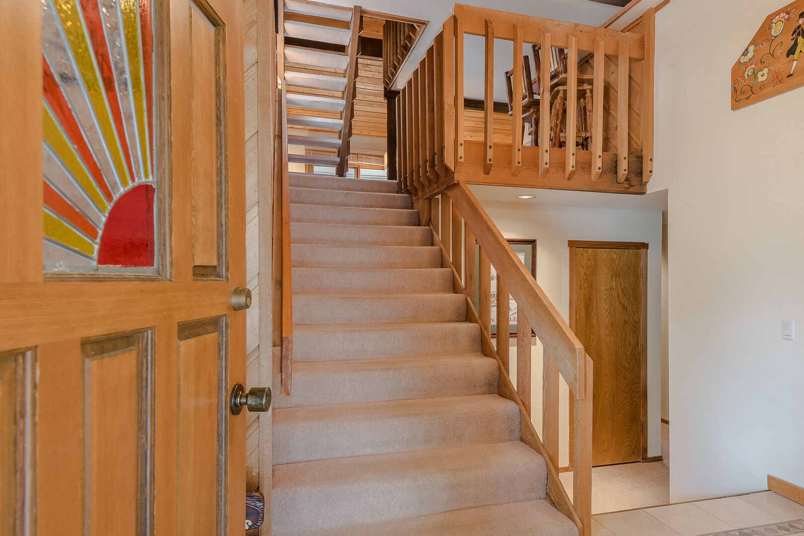 A staircase with wooden railings and carpeted steps leading to a landing.
