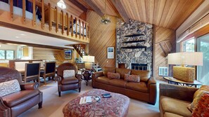 A spacious living area with a fireplace, leather furniture, and a high ceiling with wooden beams.