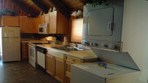 A compact kitchen with wooden cabinets, a built-in oven, a sink, and a dishwasher. - Rustic Mountain Condo (Whitefish)