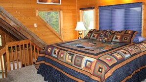 A bedroom with a large bed, a window, a lamp, and a picture on the wall. - Rustic Mountain Condo (Whitefish)