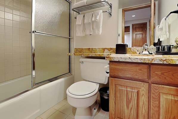 Un baño con ducha, inodoro y armarios de madera.