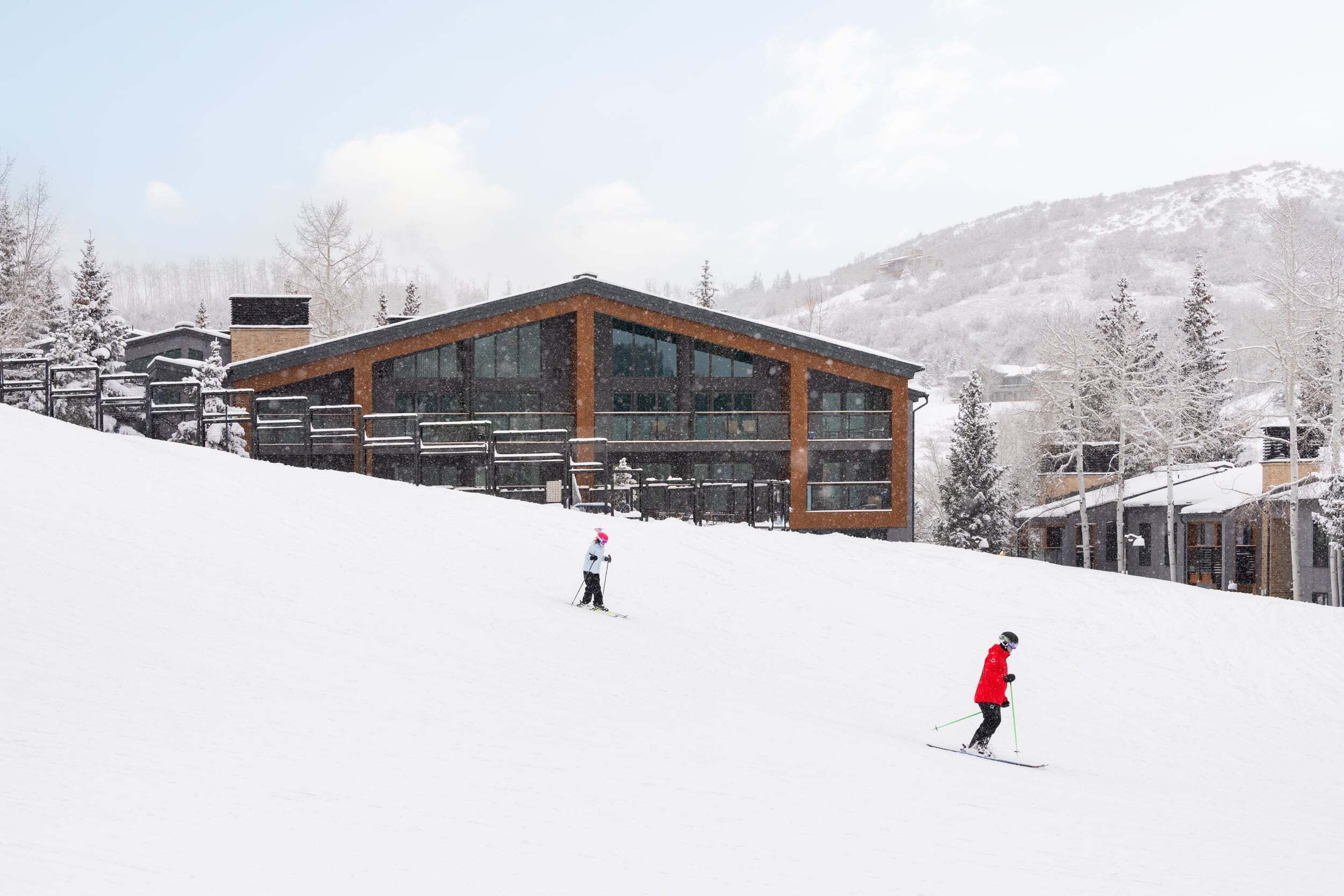 Un centro de esquí con un edificio moderno, pistas de nieve y árboles cubiertos de nieve.
