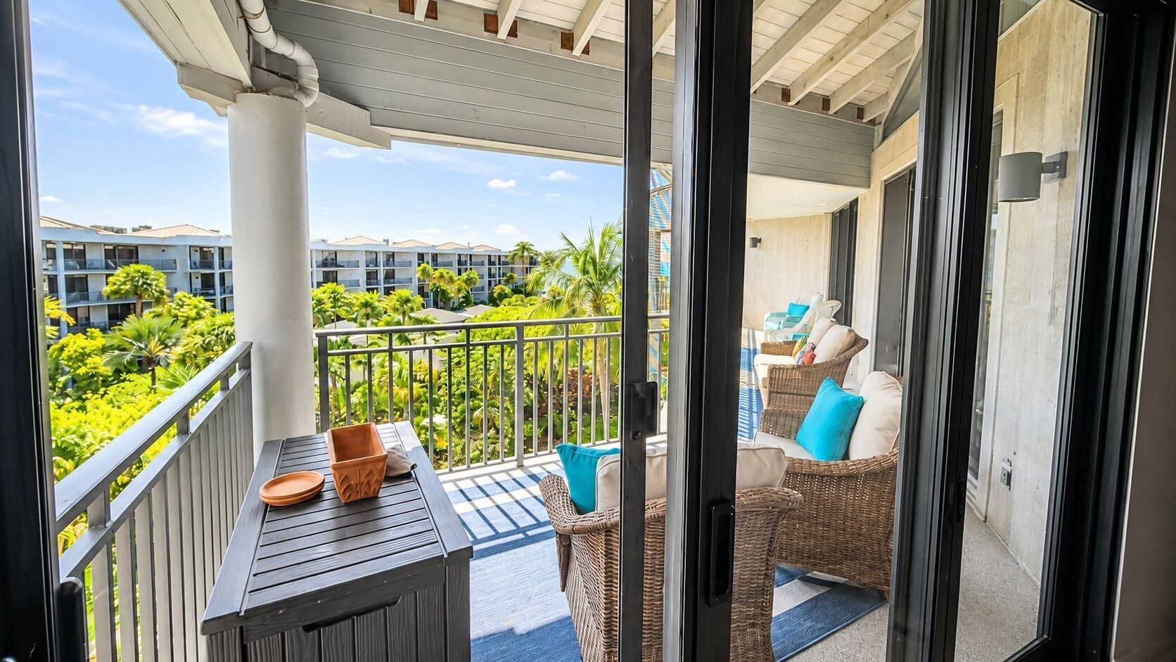 A balcony with a table, chairs, and potted plants.