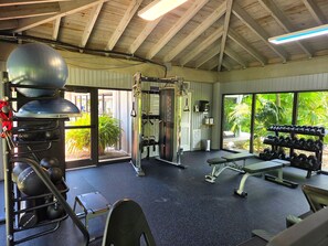 Une salle de sport équipée de machines d’exercice, d’un banc et d’un porte-haltères.