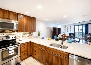 A modern kitchen with wooden cabinets, stainless steel appliances, and a large island with a sink.