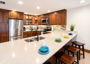 Une cuisine moderne avec des meubles en bois, des appareils en acier inoxydable et un plan de travail en granit.