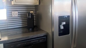 A kitchen with a stainless steel refrigerator, a dishwasher, and a coffee maker on the counter. - Lake view home with mountain views by Havasu Springs (Parker)