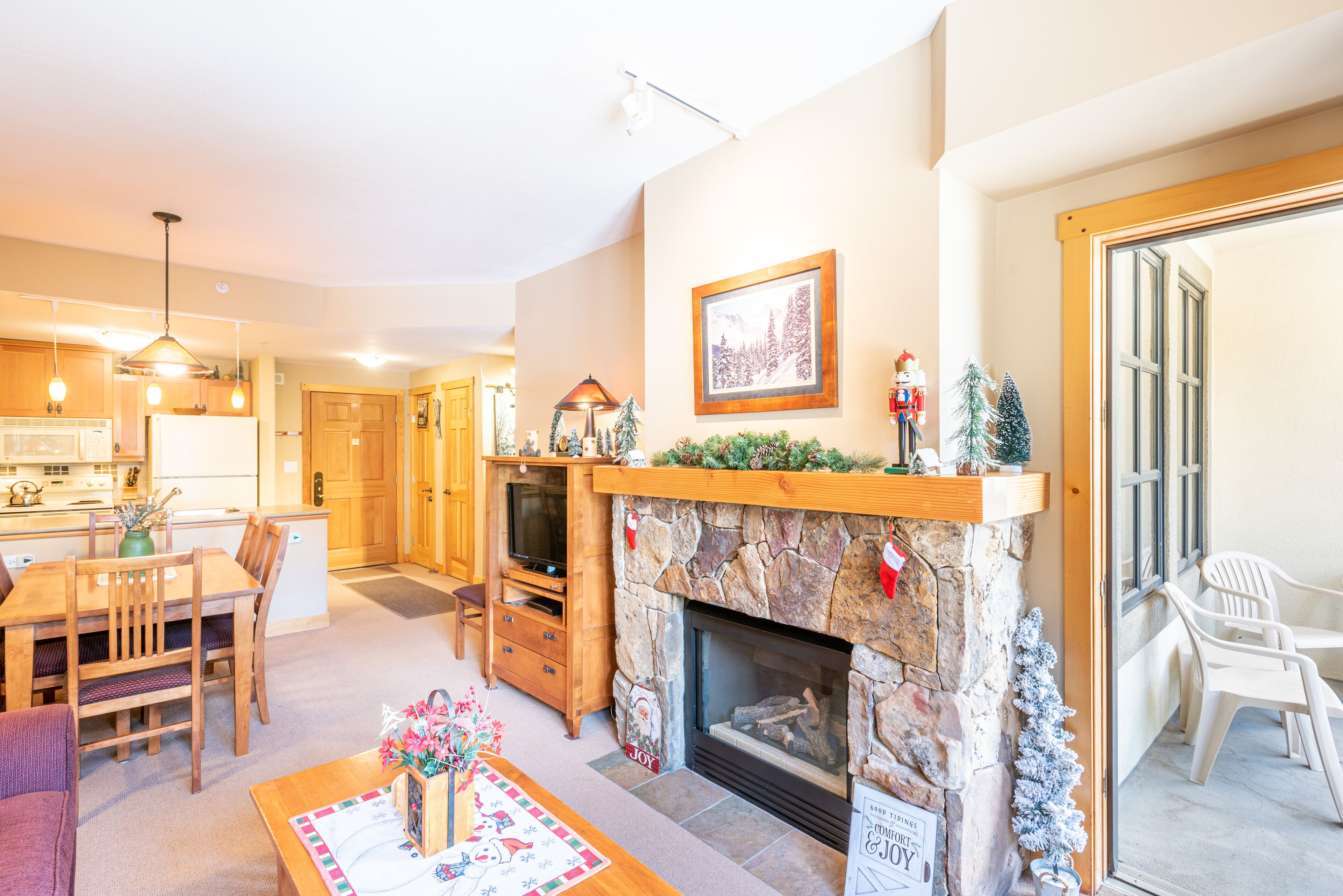 A cozy living room with a fireplace, a dining area, and a kitchen.