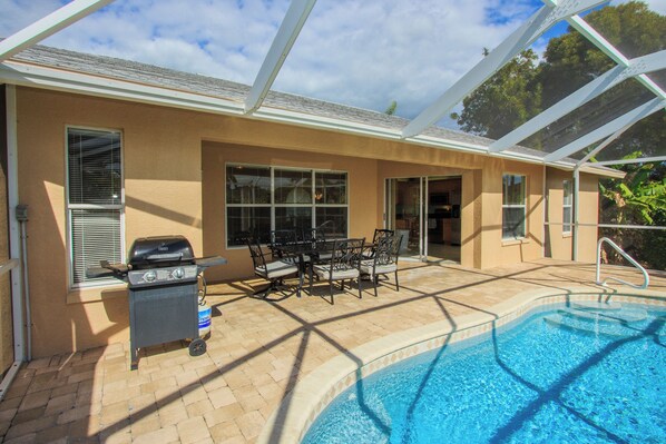 An outdoor pool area with a grill and patio furniture.