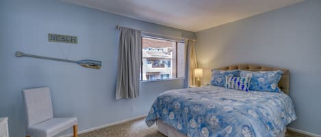 Une chambre à coucher avec un lit, une chaise, une fenêtre avec des rideaux et un tableau accroché au mur.