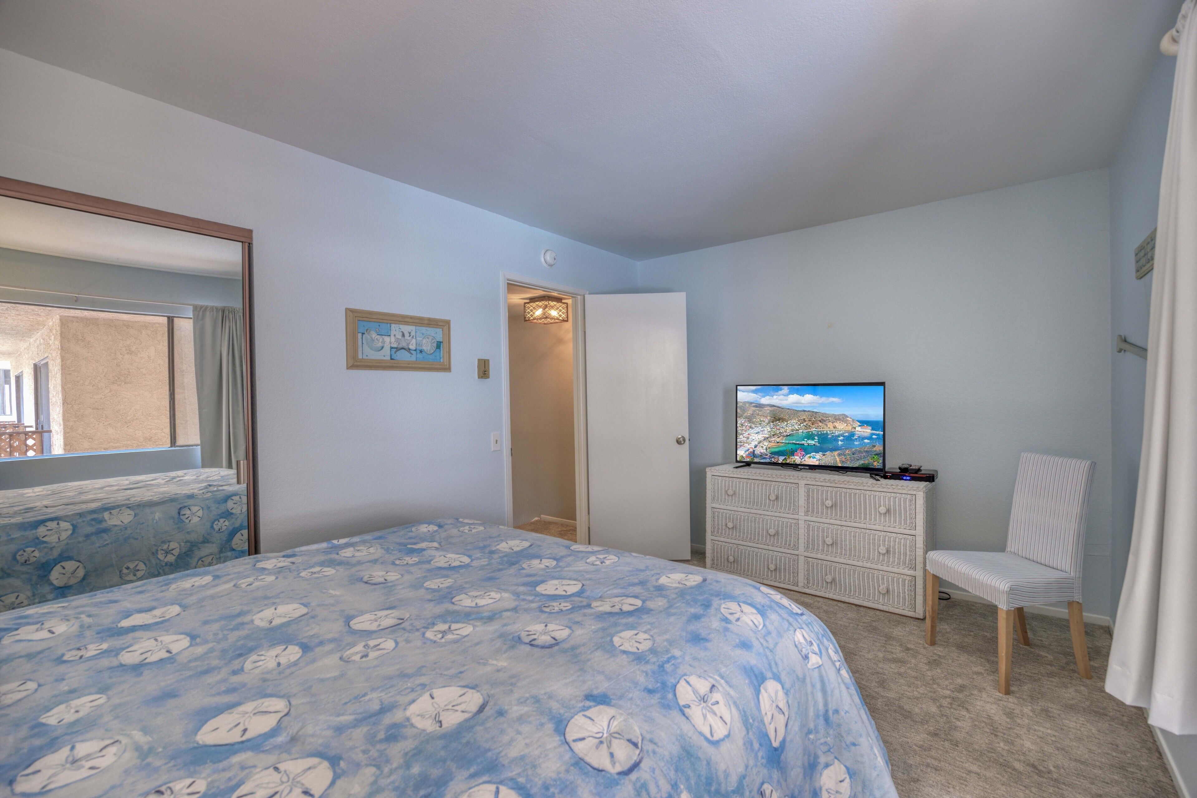 Une chambre à coucher avec un lit, une commode, un téléviseur et une chaise.