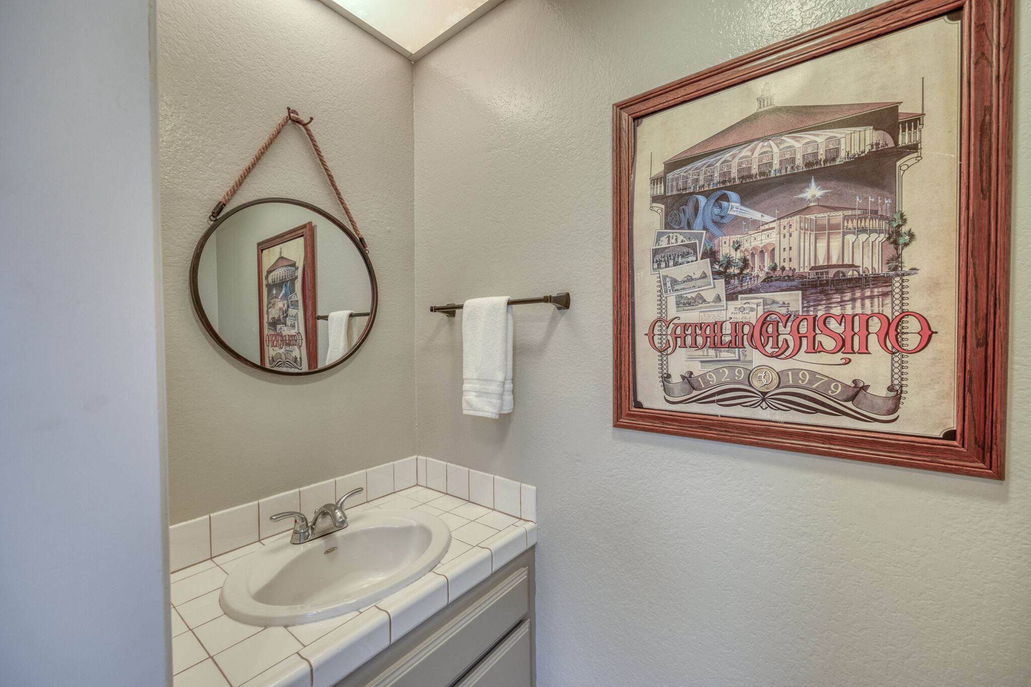 A bathroom with a sink, mirror, and a framed picture of a casino.