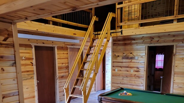 A wooden interior with a pool table, a wooden ladder, and a door. - Black Hills Get-Away! (Custer)
