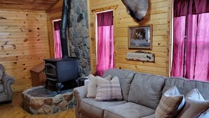 A cozy cabin interior with a stone fireplace, a mounted deer head, and a leather sofa. - Black Hills Get-Away! (Custer)