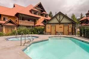A pool area with a hot tub, a wooden building with a red roof, and a sign indicating a no diving zone. - Stoney Creek Sunpath 47 (Whistler)