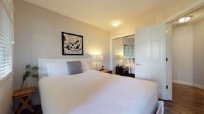 Een hotelkamer met een groot bed, nachtkastjes, een spiegel en een ingelijste afbeelding aan de muur.