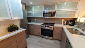A modern kitchen with stainless steel appliances, wooden cabinets, and a white countertop. - Renovated, Whistler Village Condo, Private Hot Tub, BBQ & Pool Access. (Whistler)