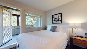 A bedroom with a large bed, a bedside table with a lamp, and a framed picture on the wall.
