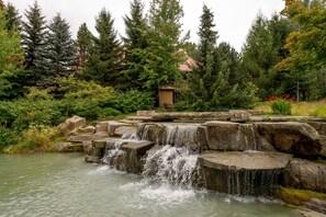 A natural landscape with a waterfall, rocks, and trees. - Stoney Creek Sunpath 47 (Whistler)