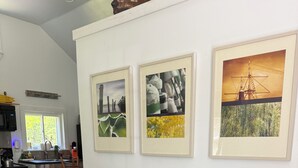 A living room with a grey sofa, two armchairs, a coffee table, and three framed pictures on the wall.