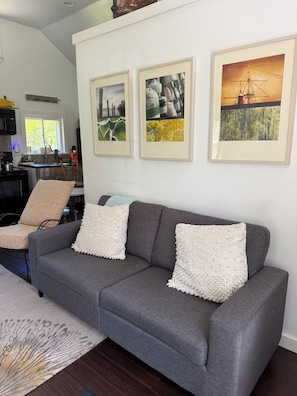 A living room with a grey sofa, two armchairs, a coffee table, and three framed pictures on the wall.