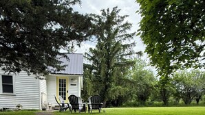 A pathway leading to a house with a yellow door, surrounded by a grassy yard and trees.