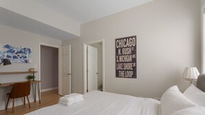 A hotel room with a large bed, a desk with a chair, a wall-mounted artwork, and a sign with Chicago addresses. - The Upscale Getaway Near Downtown (Chicago)