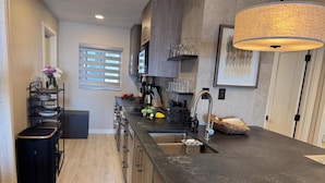 A modern kitchen with a central island, stainless steel appliances, and a hanging light fixture.