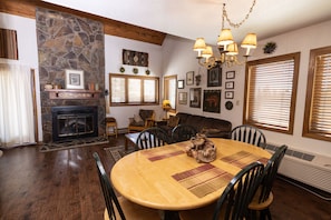 A dining area with a stone fireplace, wooden dining table, and chairs.