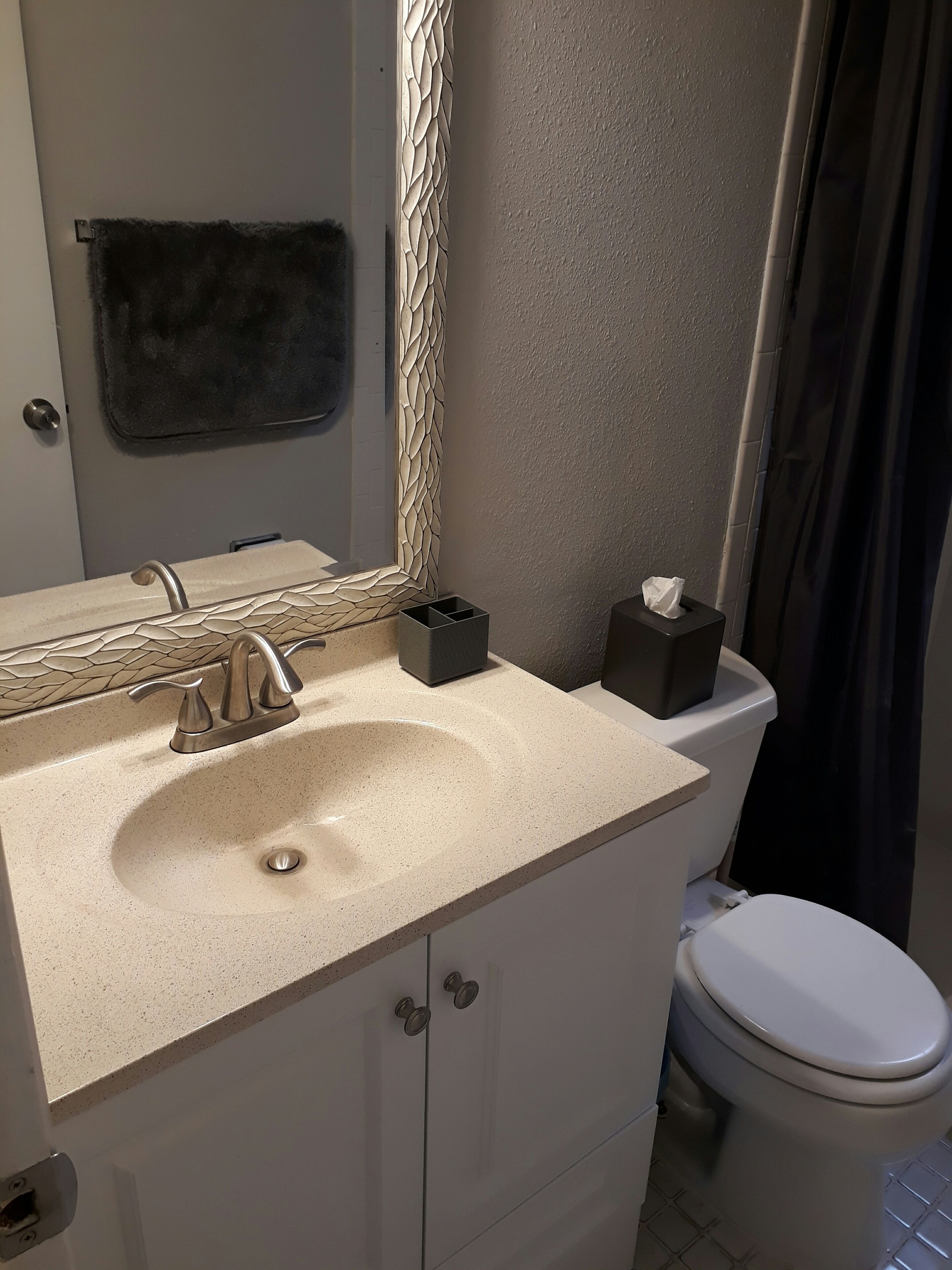 Un baño con lavamanos, espejo, inodoro y toallero.