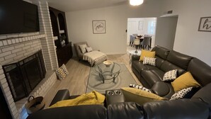 Una sala de estar con chimenea, un sofá de cuero, una mesa de centro y un televisor.