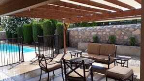 Un patio al aire libre con piscina, muro de piedra y mobiliario.
