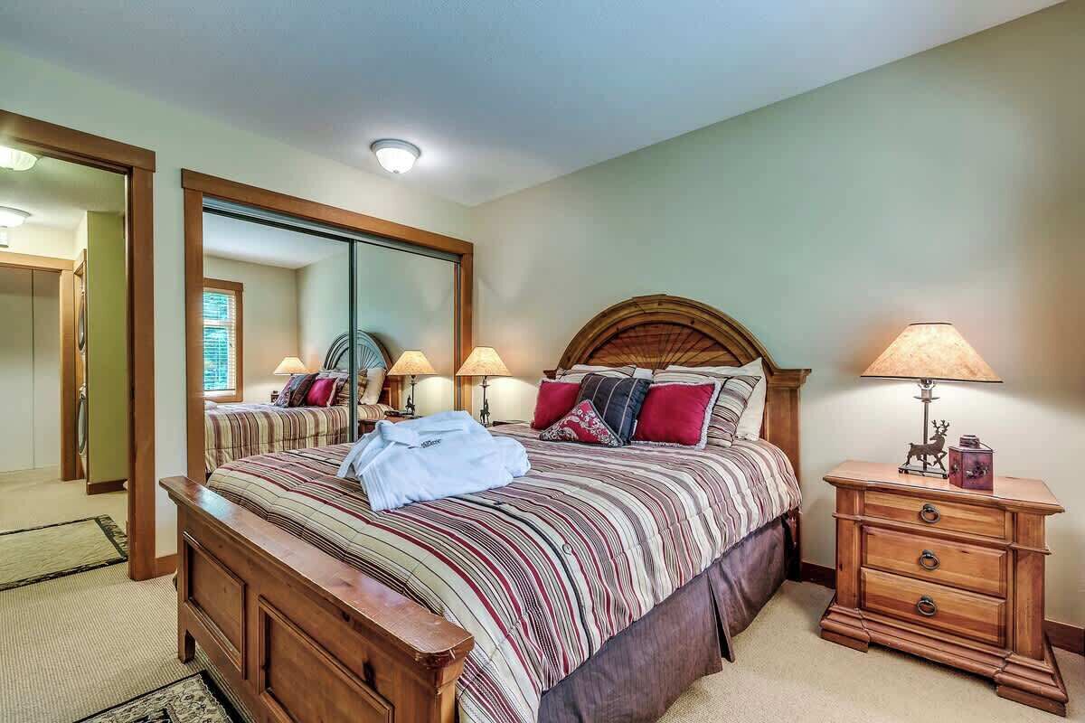 Un dormitorio con una cama grande, una mesita de noche de madera, un espejo y una lámpara.