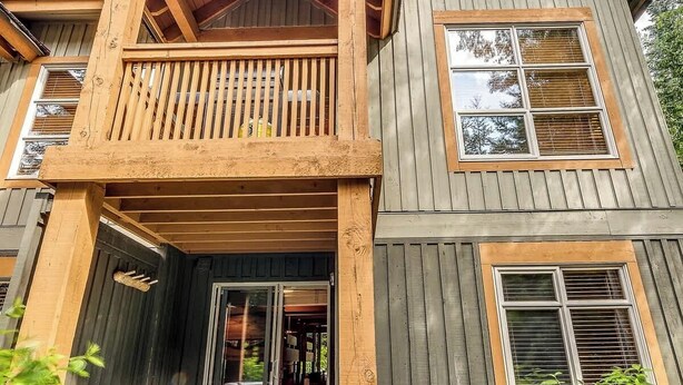 Una casa de dos pisos con un balcón de madera, un jacuzzi y un camino de piedra.