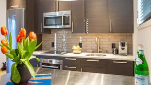 A modern kitchen with dark cabinets, stainless steel appliances, a microwave, and a sink.